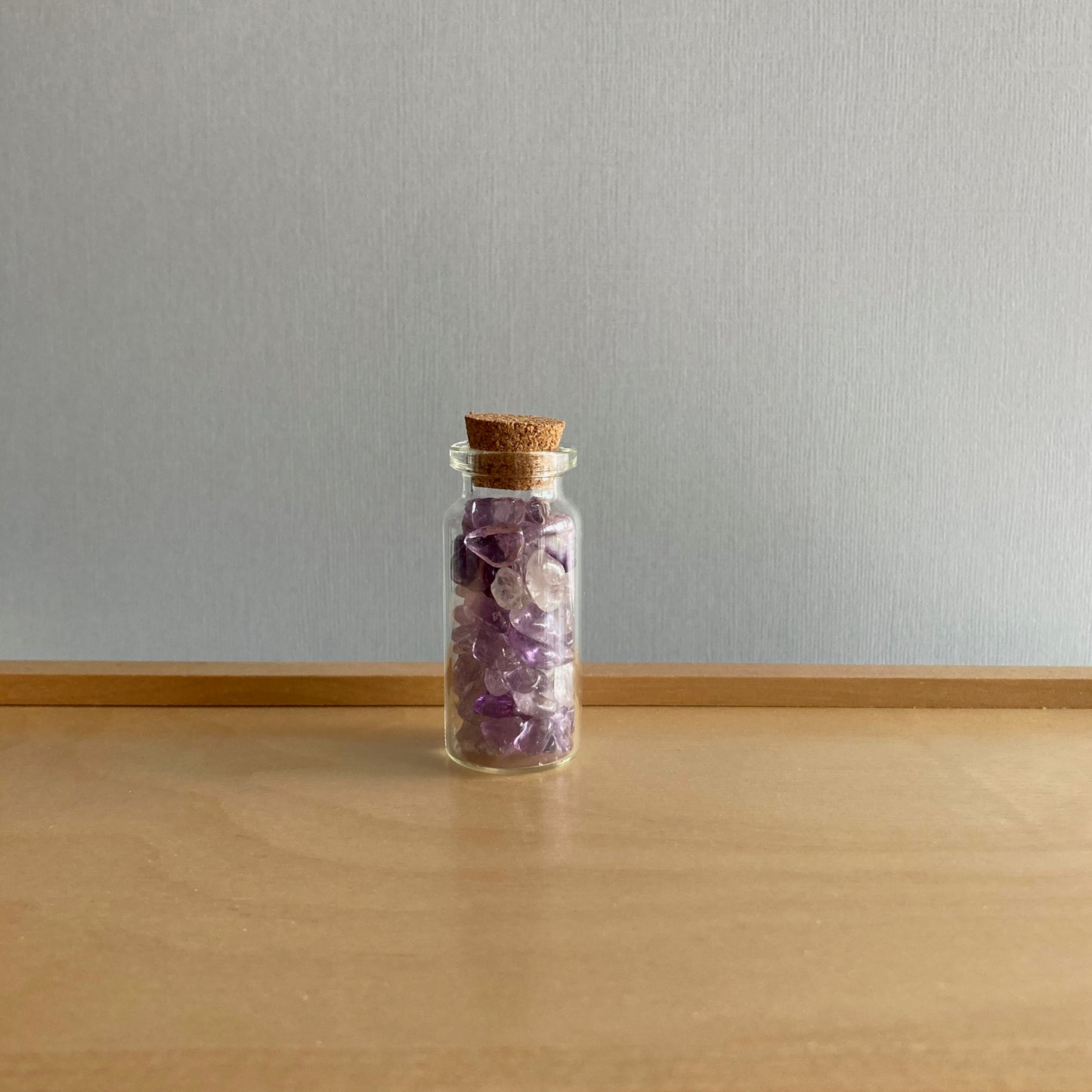 Small bottle of Amethyst chips on a wooden box