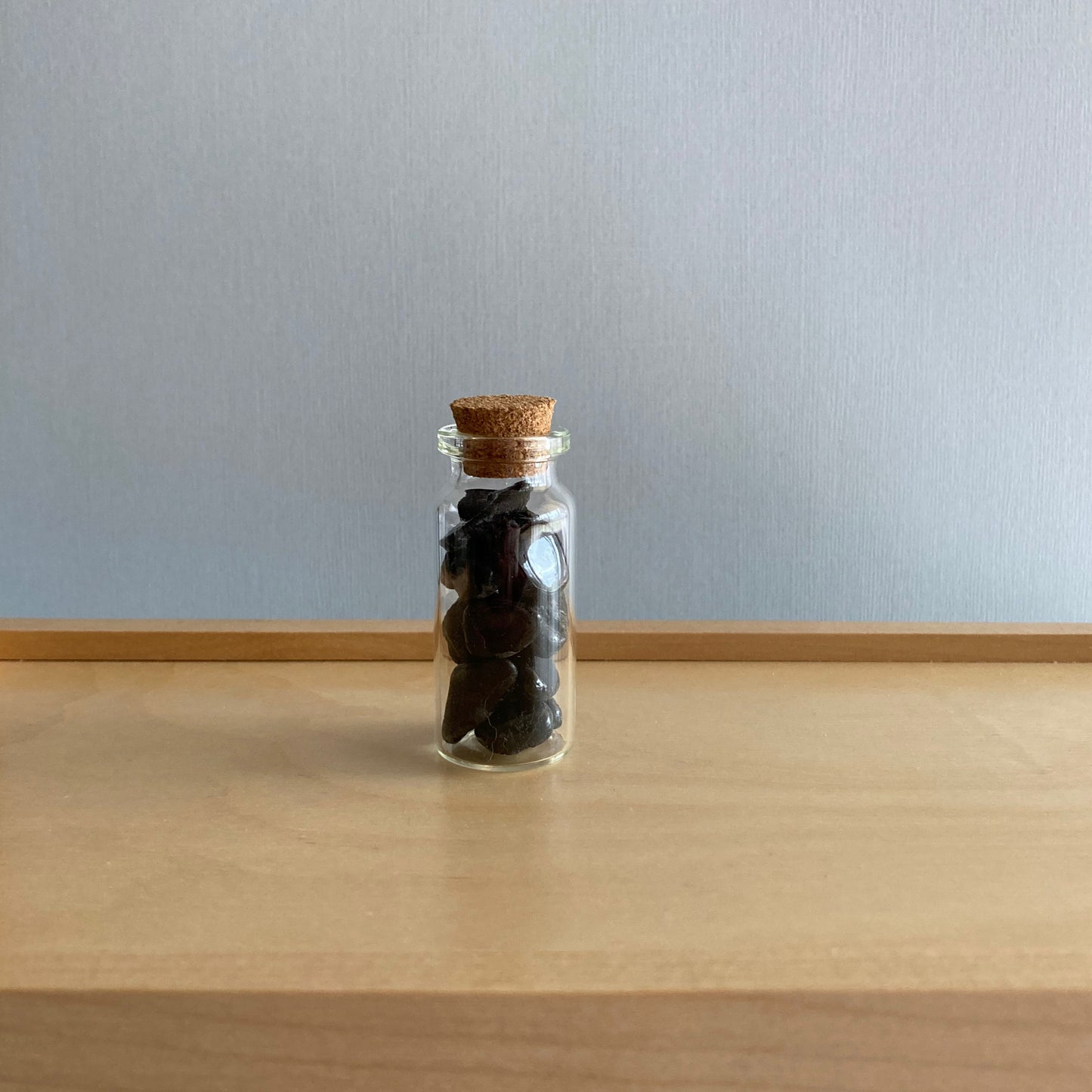 Bottle of Black Tourmaline chips sitting on a wooden box